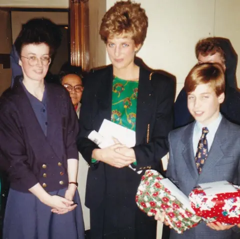 The Passage Diana, Princess of Wales, and Prince William at The Passage charity. The prince is carrying two Christmas presents. A nun stands to the left of the princess.