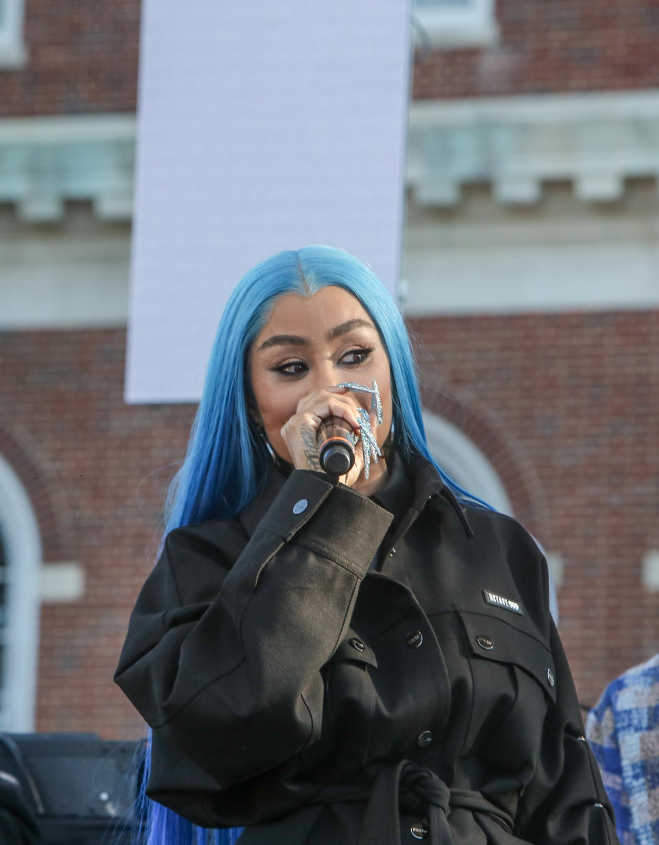 Blac Chyna in a jacket, holding a microphone near her face