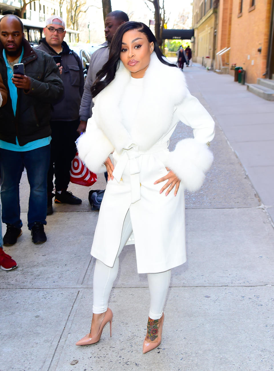 Blac Chyna in a belted coat lined with fur and tights with pointed toe heels