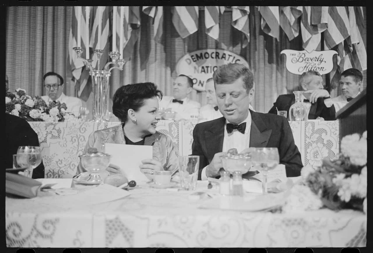 A woman and a man sit at a table in a black and white image