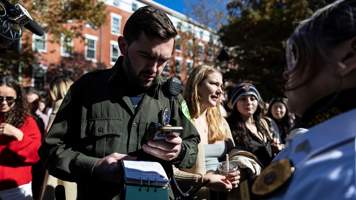 An officer from the Parks Enforcement Patrol writes a ticket to the organizer of the Timothee Chalamet lookalike contest in Washington Square Park