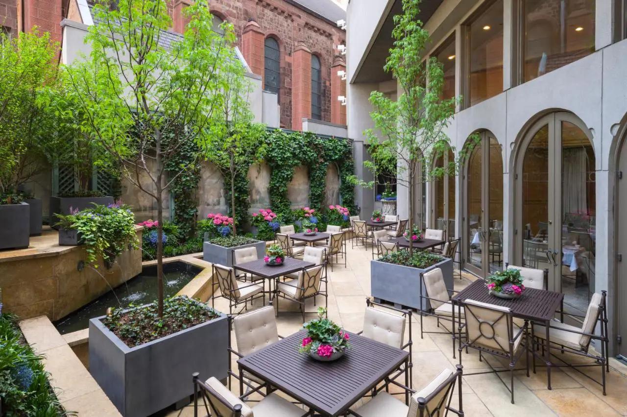 The elegant courtyard garden at The Rittenhouse Hotel, a serene outdoor dining space surrounded by greenery.