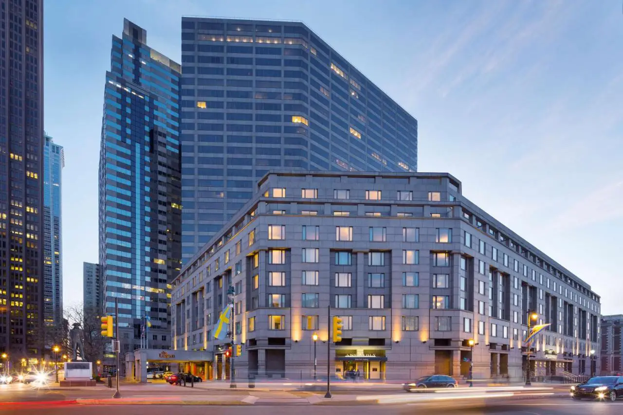 The modern exterior of The Logan Philadelphia, Curio Collection by Hilton, surrounded by the city’s skyscrapers at dusk.